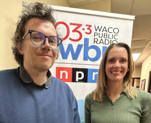 A man and a woman standing in front of a banner reading 103.3 FM, Waco Public Radio, KWBU, NPR